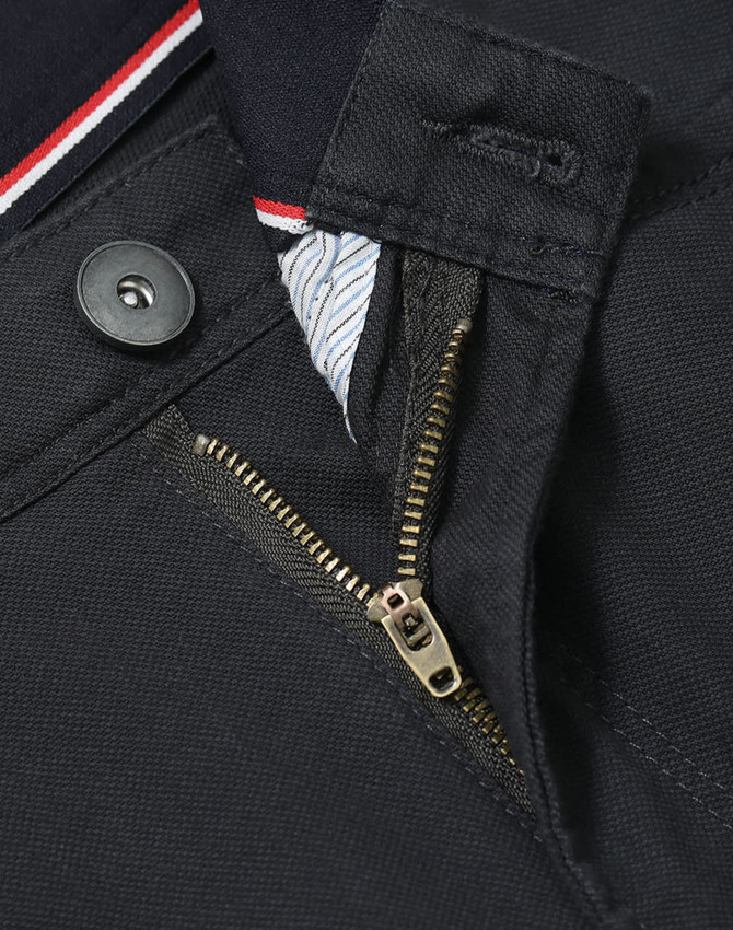A close-up of the zipper and button detail on a pair of black flexi chino pants, featuring a branded label.