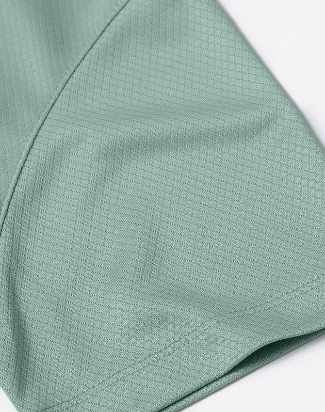 A close-up of a mint green jacquard knit fabric, showcasing its texture and pattern detail.