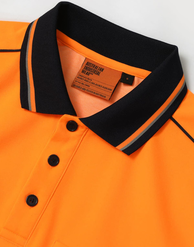 An orange safety polo shirt with black collar and buttons, featuring a tag with care instructions.