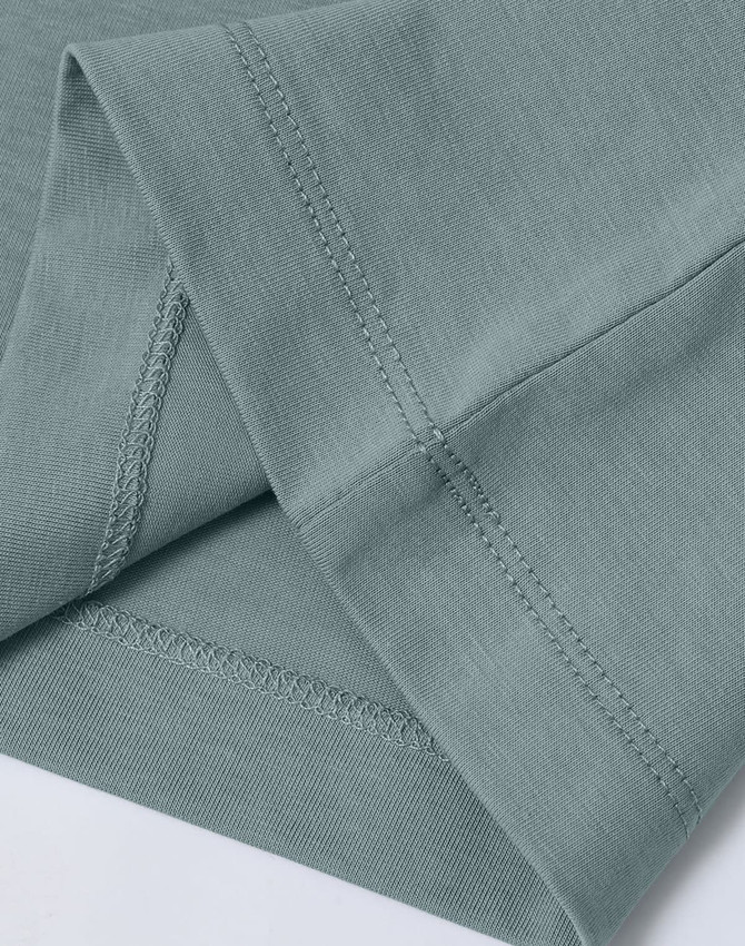 A close-up of a light green premium cotton T-shirt, highlighting the sleeve and stitching details.