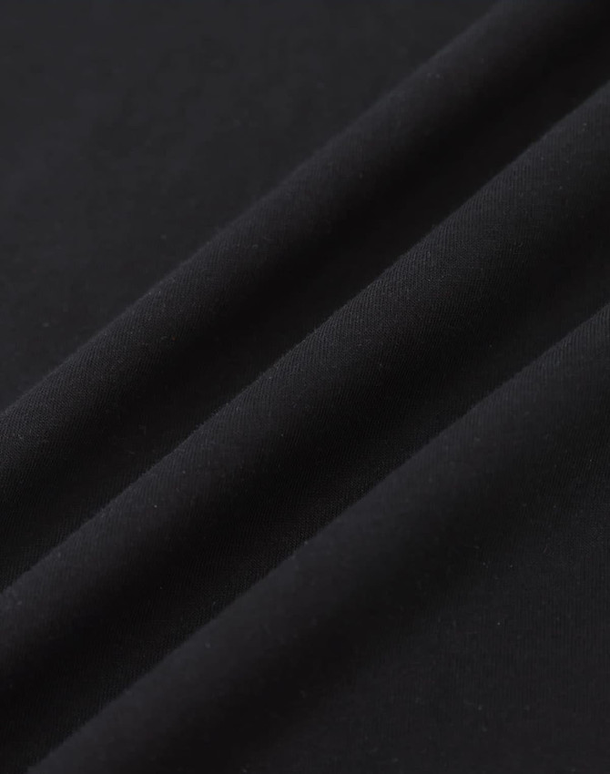 A close-up of black cotton fabric with a smooth texture, featuring subtle folds.