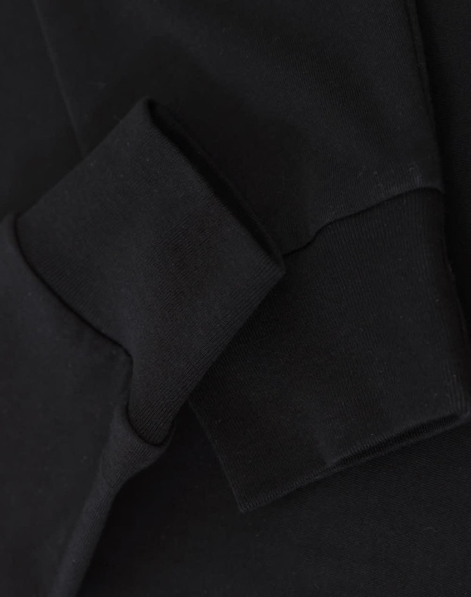 A close-up of black long-sleeve cotton tee shirt cuffs, featuring a visible logo.