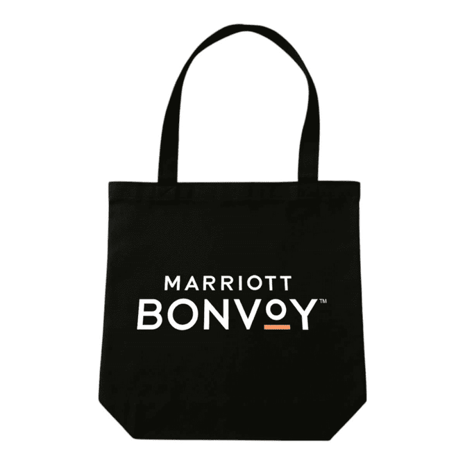 A black tote bag with handles, featuring a logo on the front, placed on a wooden table.
