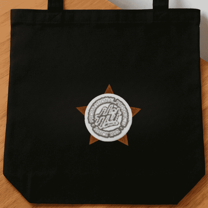 A black tote bag featuring a circular logo set within a star design.