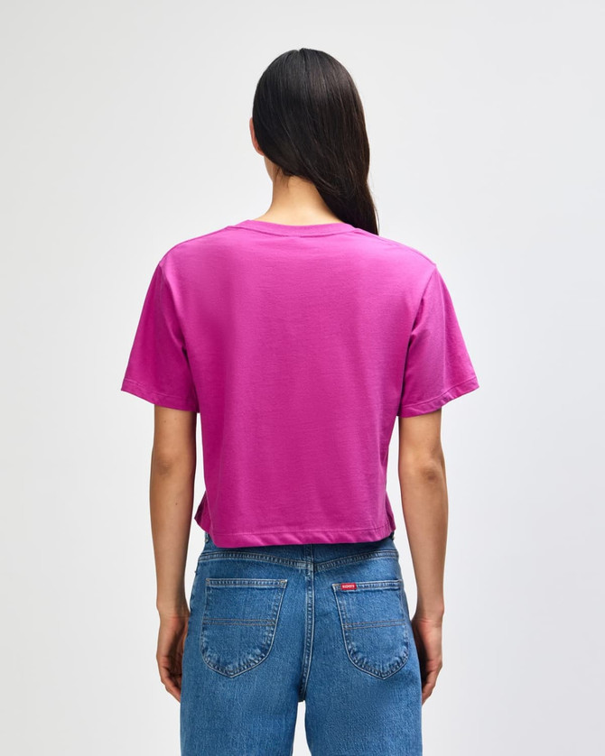 A women's fine jersey boxy T-shirt in magenta colour, featuring a plain back design. The model wears denim jeans.