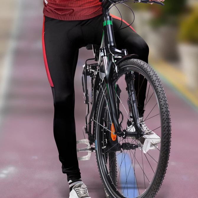 A pair of black cycling pants with red accents, featured on a cyclist's legs while riding a bike.