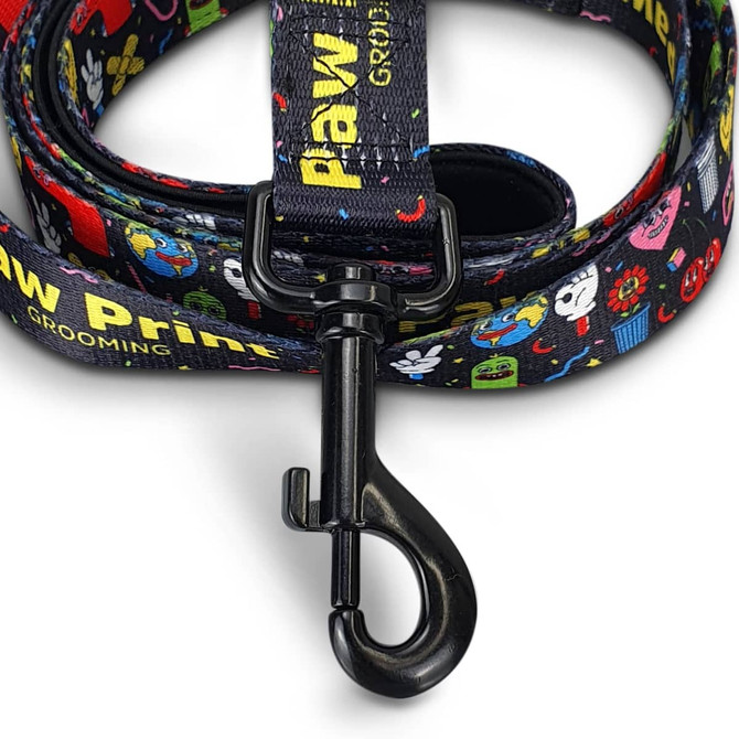 A dog leash featuring a black background with colourful, cartoon-style graphics and a sturdy metal clip.