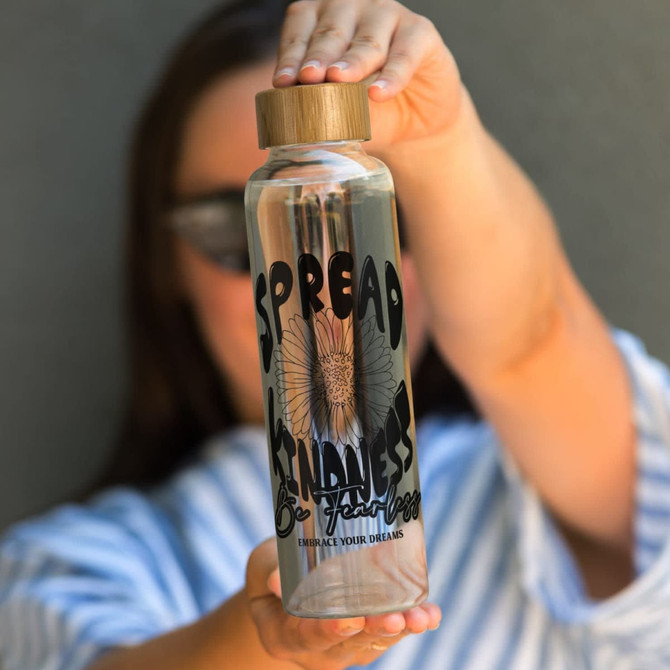 A drink bottle with a bamboo lid, featuring a clear glass body and decorative black text design.