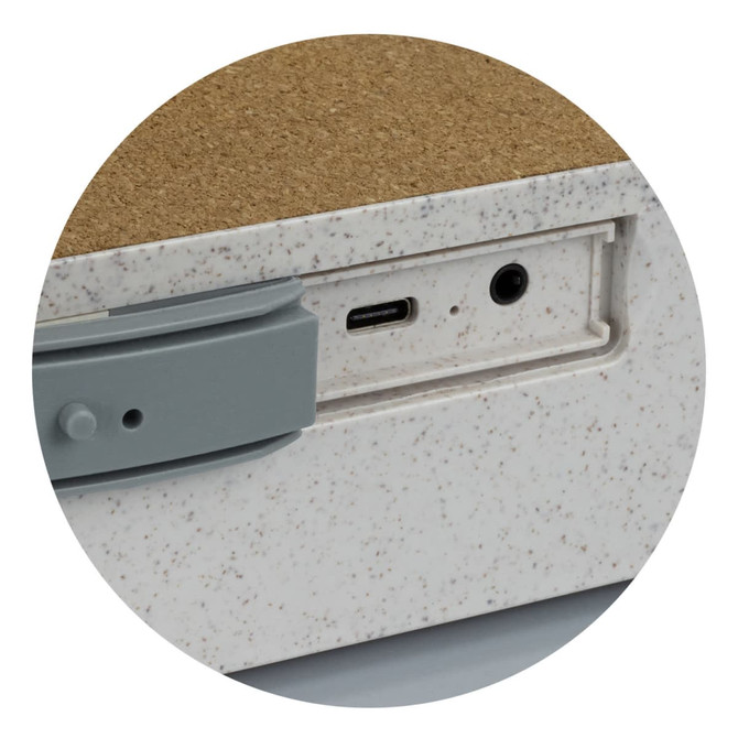 A close-up of a wireless charger with a textured surface, featuring a USB-C port and a headphone jack in grey.