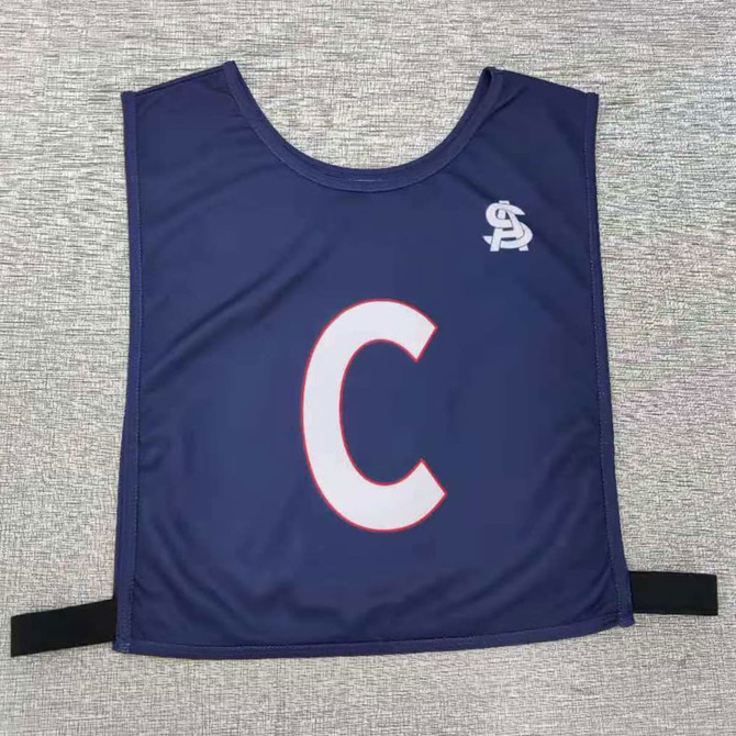 A navy blue pull-over elastic netball bib with a large white ‘C’ and a branding logo.