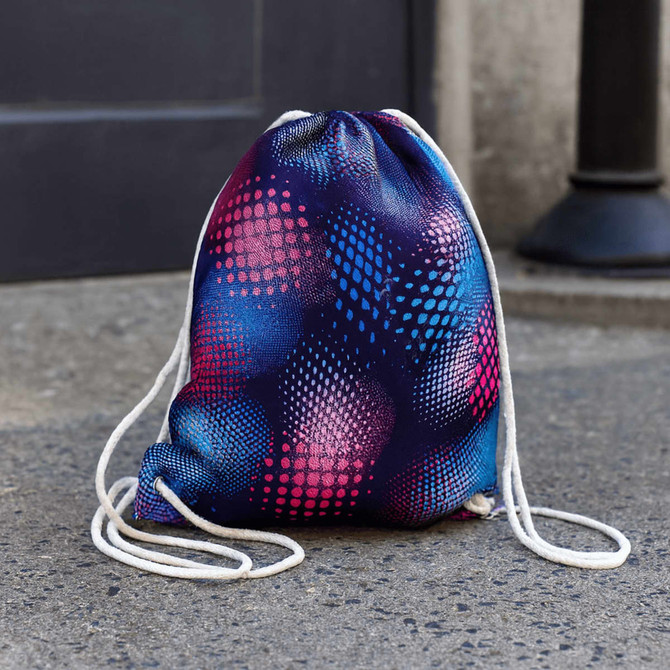 A full-colour drawstring bag featuring vibrant blue, pink, and purple dot patterns, with white drawstrings and a logo.