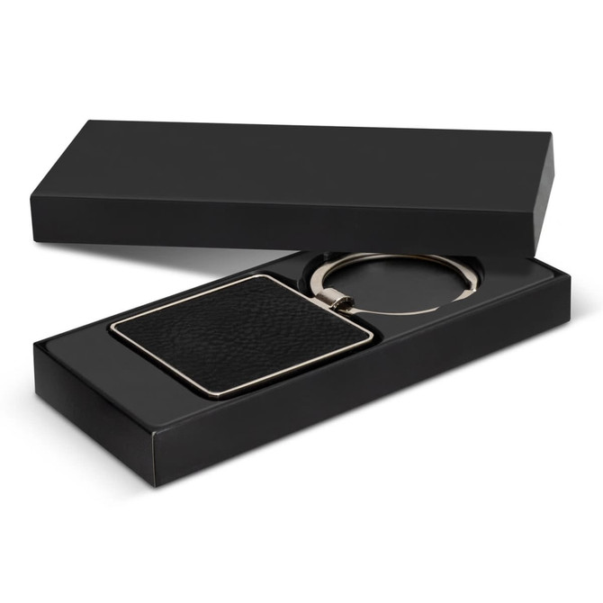 A square black key ring with a textured surface, presented in a sleek black gift box.