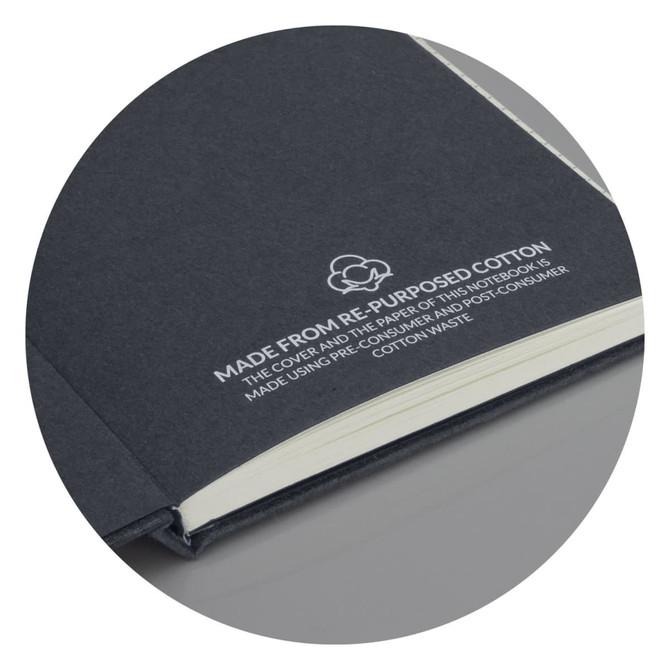A recycled cotton hard cover notebook in dark grey with a logo, featuring cream-coloured pages inside.