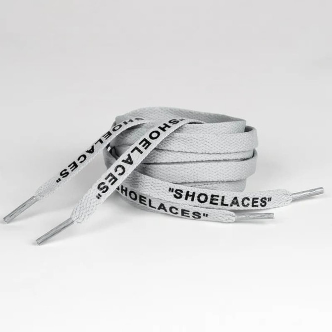 A pair of grey shoelaces featuring the word "SHOELACES" printed along their length, with metal tips at the ends.