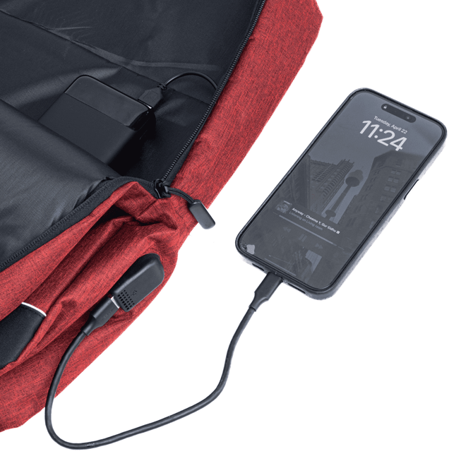 A red backpack with a charging port connected to a smartphone. It features a built-in power bank and a logo.