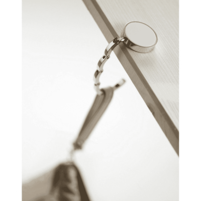 A silver bag hanger attached to a table edge, featuring a circular base and chain link design.