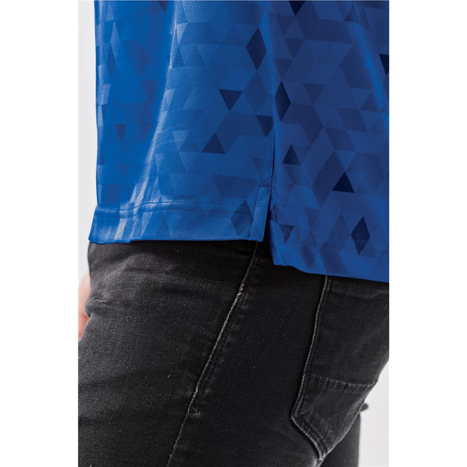 A blue polo shirt featuring a geometric pattern, with a side view showing the hem detail. The shirt has branding.