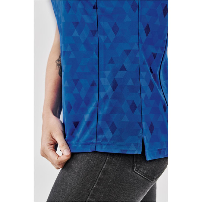A close-up of a women's polo shirt in blue featuring a geometric pattern, with a side slit and a logo.