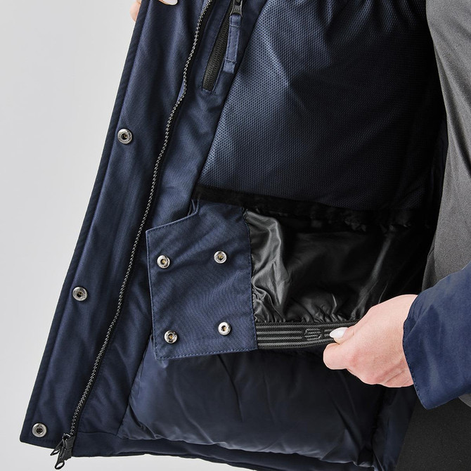 A navy puffer jacket interior featuring pockets with snap fasteners and a soft lining. It has a branded label.