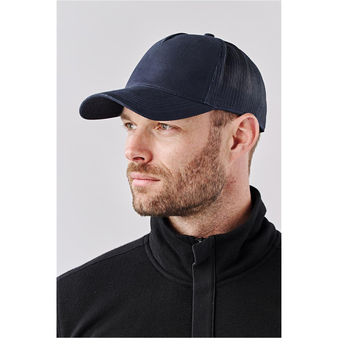 A navy trucker cap featuring a mesh back and a solid front panel, shown on a model against a neutral background.