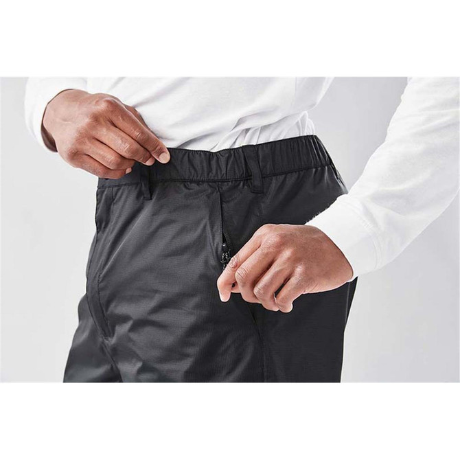 A pair of black track pants with an elastic waistband and a side zip pocket. The model shows the waistband.