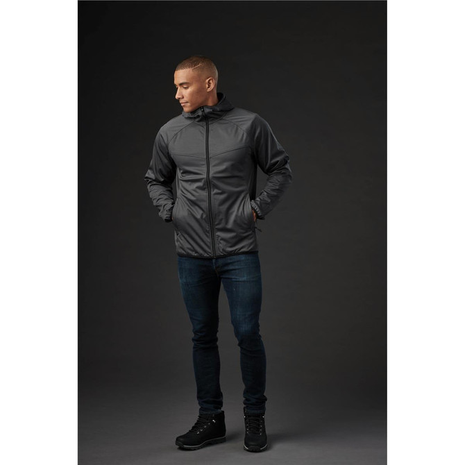 A grey men's softshell jacket with a hood, shown on a model wearing dark jeans and footwear, featuring a logo.