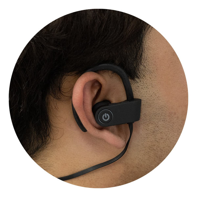 Bluetooth earbuds in black worn over the ear, featuring a power button on the side.