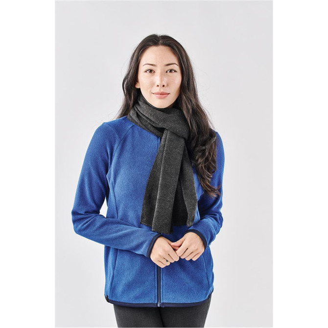 A woman wearing a dark grey knit scarf over a blue jacket, posing against a light background.