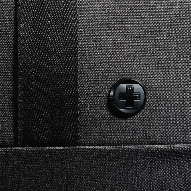 A black duffle bag with a textured surface and a circular logo on the side.