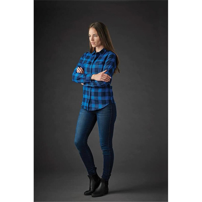 A blue plaid women's button-up shirt with a snap front, paired with skinny jeans and ankle boots.