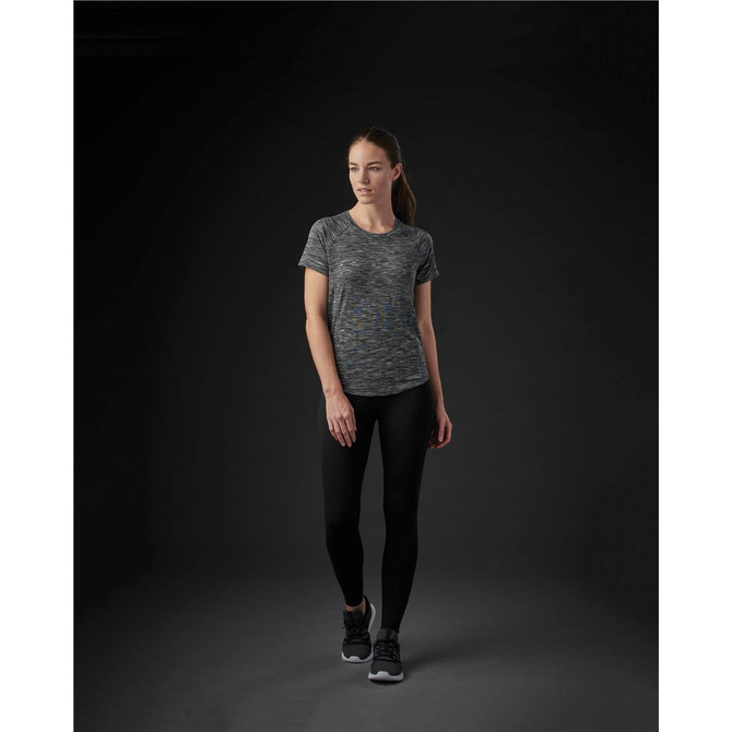A woman wearing a grey and black marled women's Pacifica tee paired with black leggings. The image features a logo.