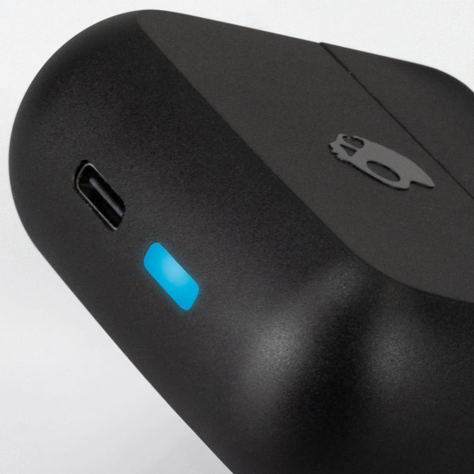 A close-up of black Skullcandy Mod TWS Earbuds case with a blue LED light and a logo.
