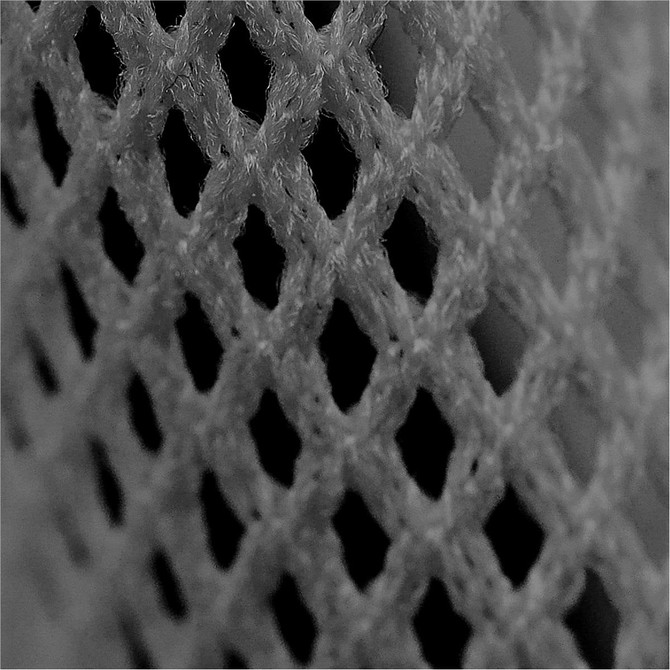 A close-up of grey mesh fabric featuring a diamond pattern, highlighting the texture and weave.