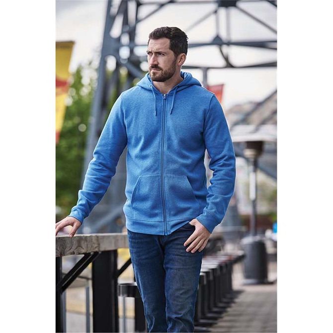 A blue fleece full zip hoody worn by a man, standing outdoors near a railing with urban scenery.