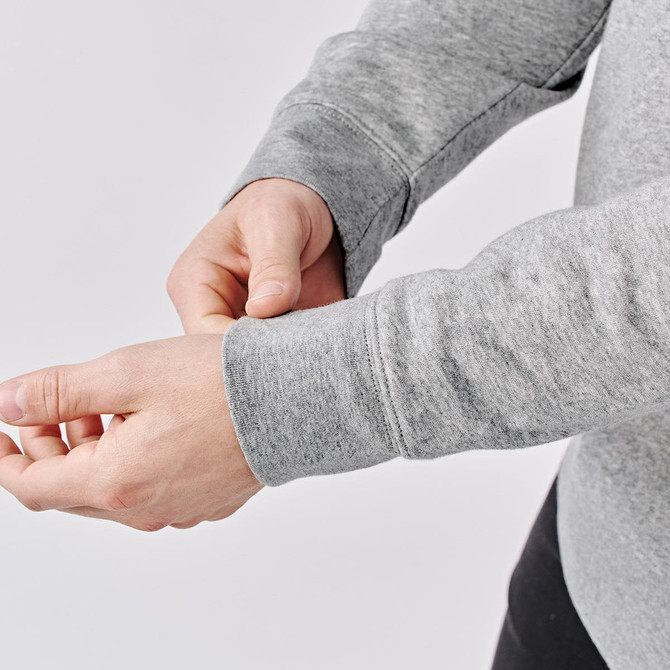 A grey 1/4 zip pullover with long sleeves, featuring wrist cuffs, held by a person.