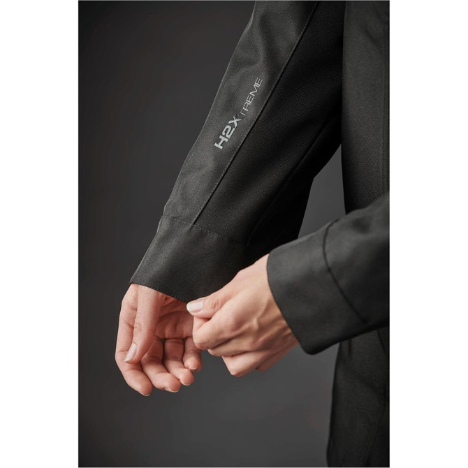 A close-up of a woman's sleeve on a dark green jacket featuring a logo on the arm.