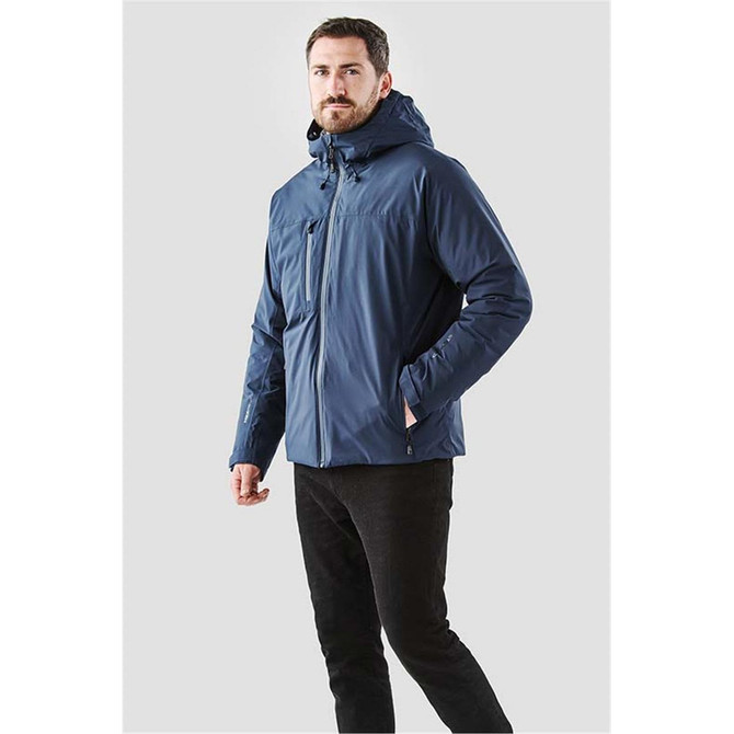 A navy thermal shell jacket with a hood, featuring a front zip and side pockets. The model stands confidently.