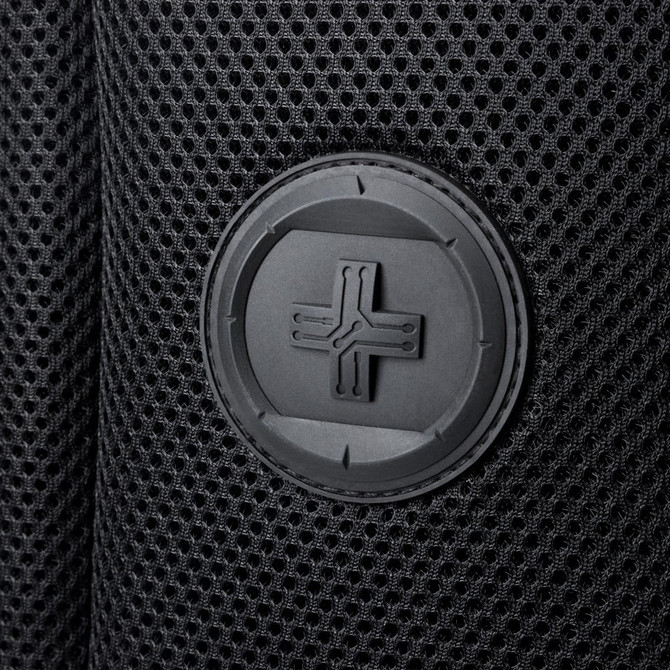 A close-up of a black mesh fabric featuring a round logo patch.