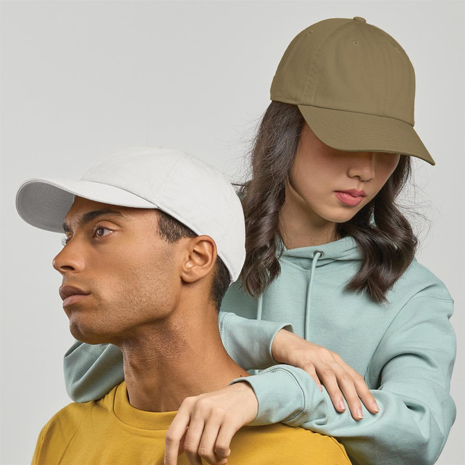 Two people wearing caps; one in white and the other in olive green, against a neutral background.