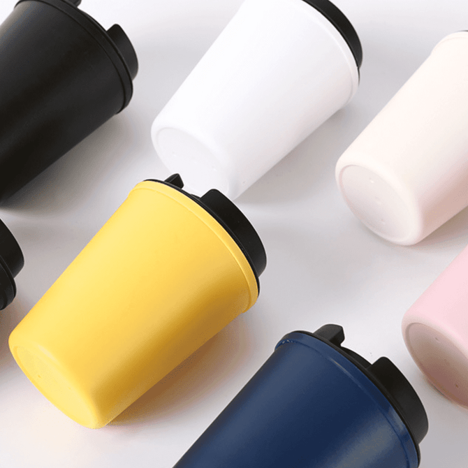 A collection of travel mugs in black, white, yellow, blue, pink, and pale pink, featuring a lid and branding.