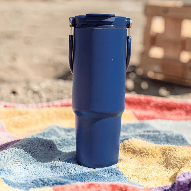 A drink bottle in navy blue with a lid and handle, placed on a colourful towel.