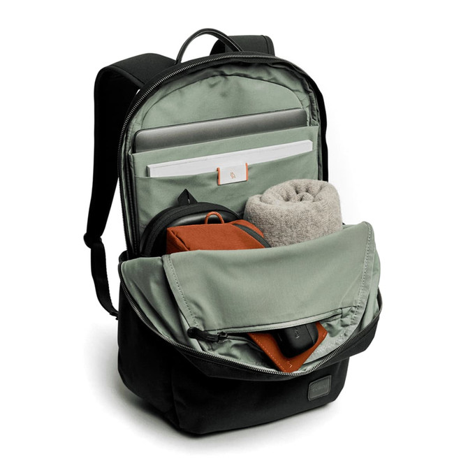 A black daypack with a green interior, featuring compartments for a laptop, a towel, and a small pouch.