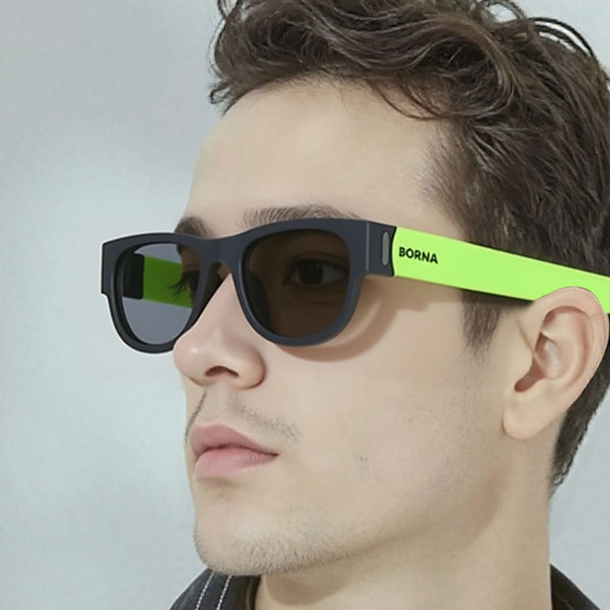 Sunglasses featuring a black frame and vibrant green arms, displayed on a model's face.
