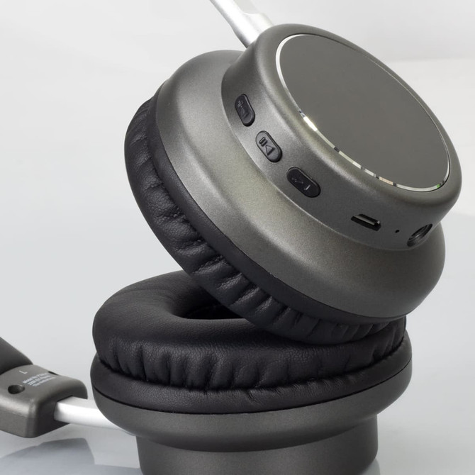 A pair of wireless headphones in grey with padded ear cushions and various control buttons on the side.