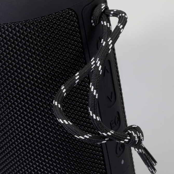 A black Bluetooth speaker with textured surface and a decorative cord attached.