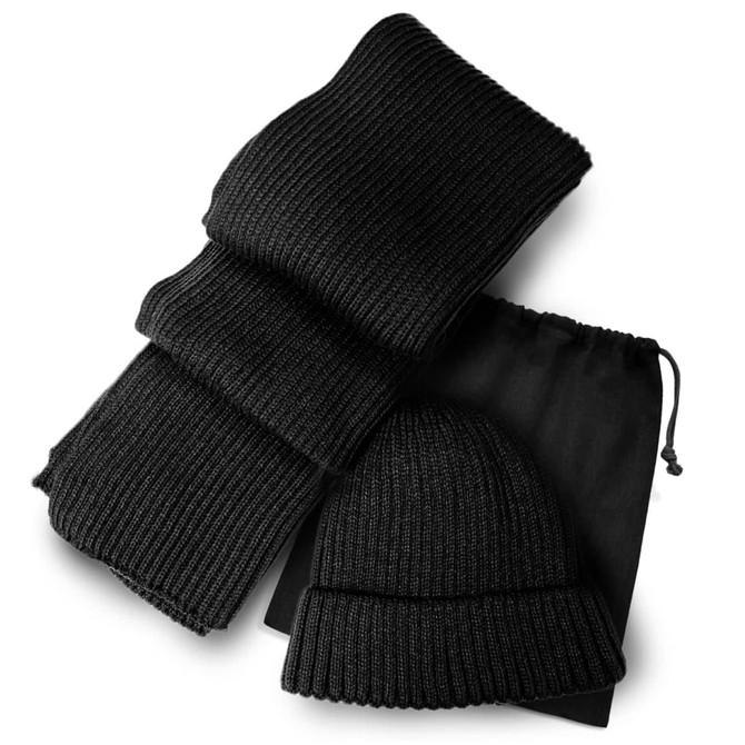 A black knitted scarf and beanie set, packaged with a drawstring bag. The scarf is folded neatly beside the beanie.