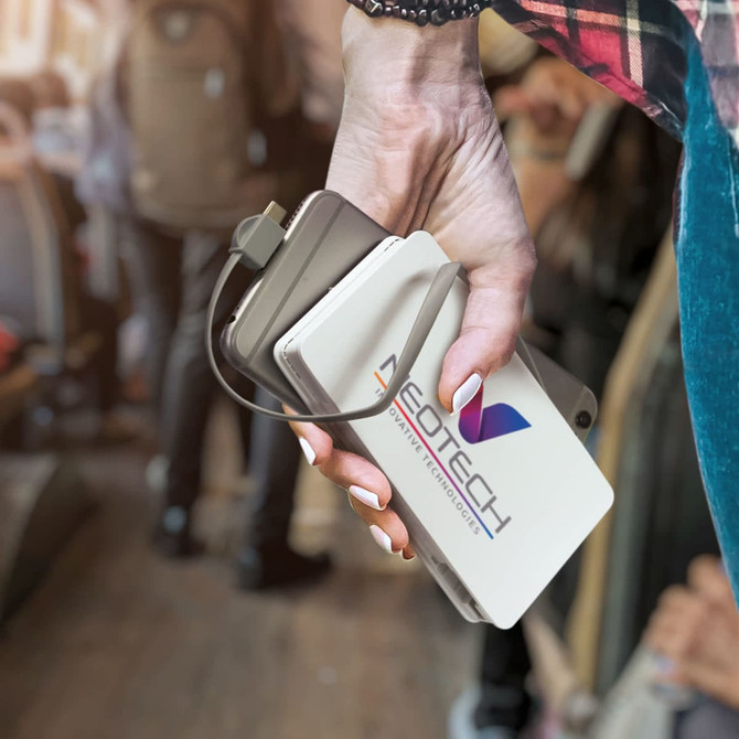 A wireless charging power bank in white with a logo, being held alongside a smartphone.