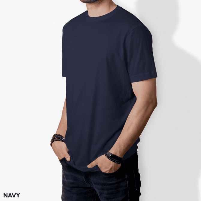 A navy T-shirt displayed on a model, featuring a simple design and short sleeves. The model has hands in pockets.