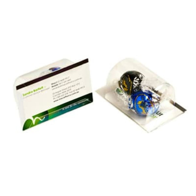 A business card holder featuring two Lindt chocolate balls, one black and one blue, in a clear packaging.