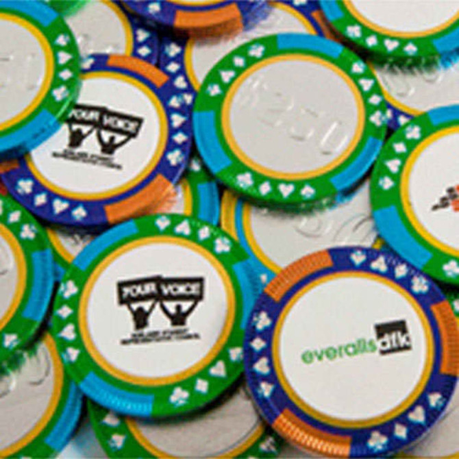 Chocolate poker chips in various colours featuring a green, blue, and orange design, with some branding on them.